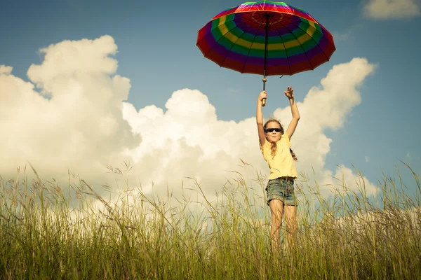 Girl jumping on the road with an umbrella in his hand — Stock Photo, Image