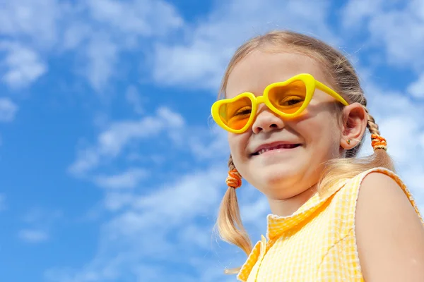 Portret van een gelukkig meisje met zonnebril tegen de hemel — Stockfoto