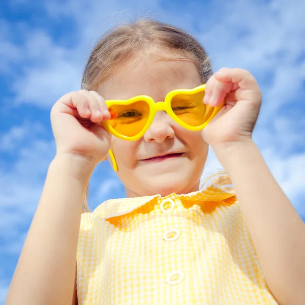 Retrato de uma menina feliz com óculos de sol contra o céu — Fotografia de Stock