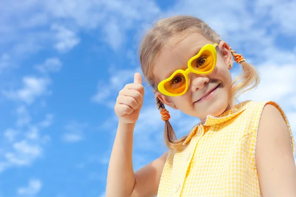 Retrato de uma menina feliz com óculos de sol contra o céu — Fotografia de Stock