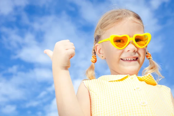 Πορτρέτο του ένα ευτυχισμένο κορίτσι με τα γυαλιά ηλίου ενάντια στον ουρανό — Φωτογραφία Αρχείου