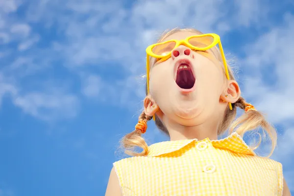 Retrato de uma menina feliz com óculos de sol contra o céu — Fotografia de Stock