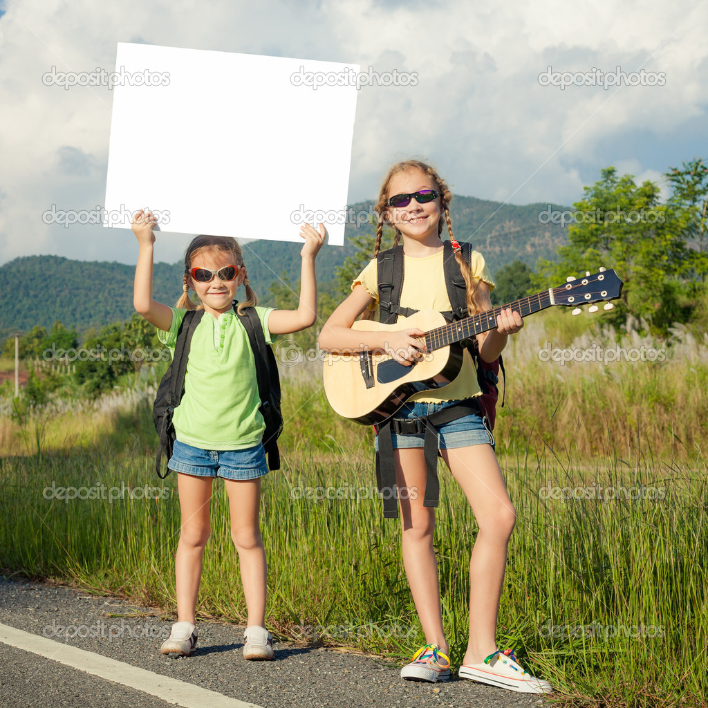 two girls with backpacks standing on roadside of the road