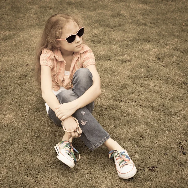 Teen flicka i parken sitter på gräset. — Stockfoto