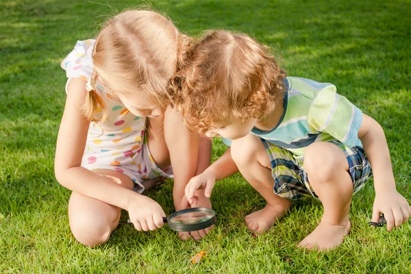 Dos niños pequeños jugando con lupa al aire libre en el d — Foto de Stock