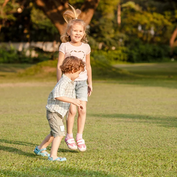 Two happy little kids playing in the park in the day time — Stock Photo, Image