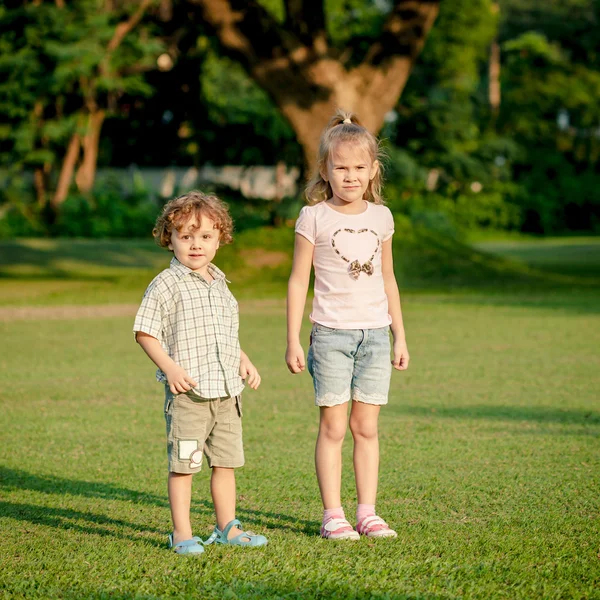 Two happy little kids playing in the park in the day time — Stock Photo, Image