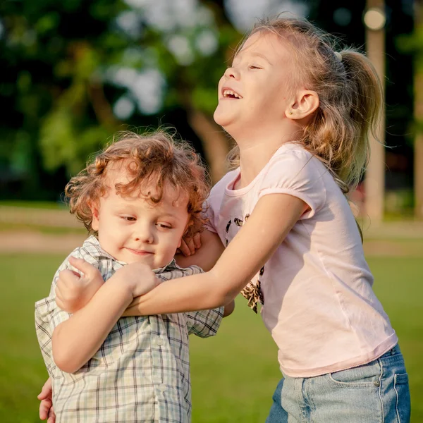 Duas crianças felizes brincando no parque durante o dia — Fotografia de Stock