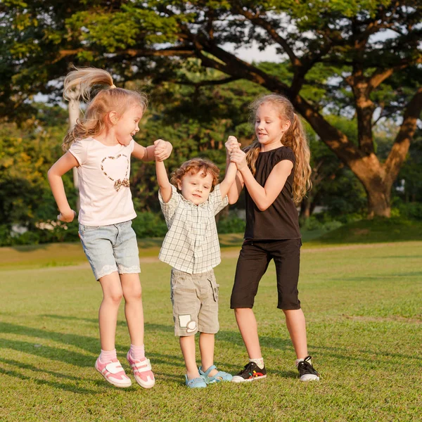 Tři šťastné malé děti hrají v parku v denní době — Stock fotografie