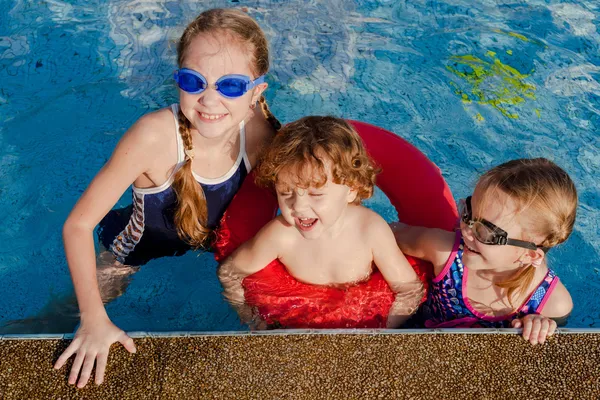 Zwei kleine Mädchen und ein kleiner Junge spielen im Pool — Stockfoto