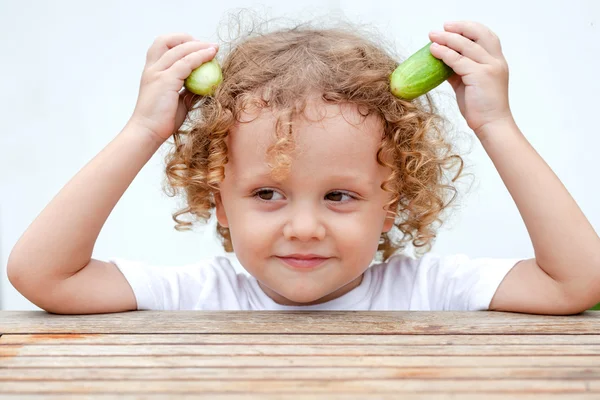 Glücklicher kleiner Junge mit einer Gurke in der Hand. Konzept der gesunden Ernährung. — Stockfoto