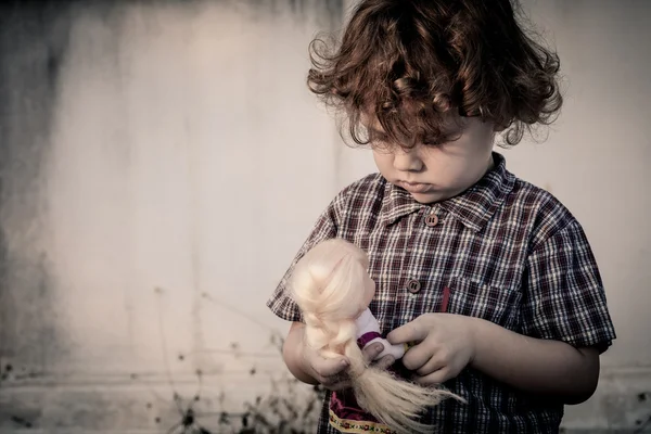 Triste niño abrazando a una muñeca — Foto de Stock