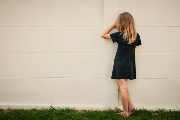 Porträt eines traurigen kleinen Mädchens, das tagsüber in der Nähe einer Mauer steht — Stockfoto