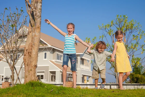 Zwei glückliche Mädchen und ein kleiner Junge stehen in der Nähe des Hauses — Stockfoto