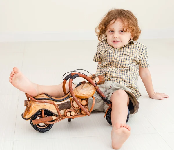 Little boy sitting on the floor and playing toy motorcycle — Stock Photo, Image