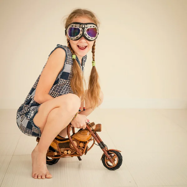 Little girl in glasses on toy motorcycle — Stock Photo, Image