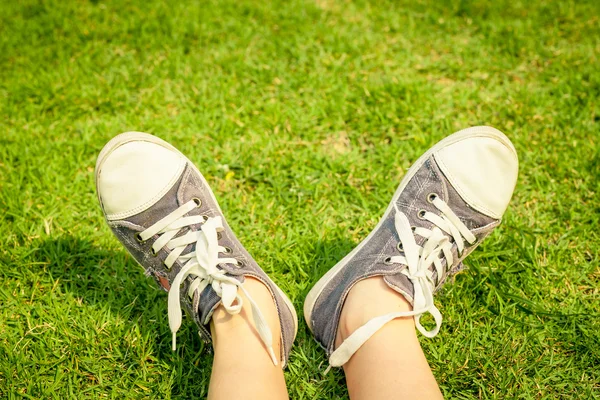 Jugend Turnschuhe auf Mädchenbeinen im Gras bei sonnigem, heiterem Sommer — Stockfoto