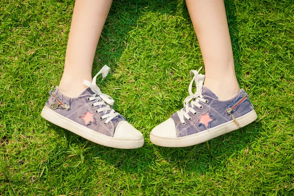 Jugend Turnschuhe auf Mädchenbeinen im Gras bei sonnigem, heiterem Sommer — Stockfoto