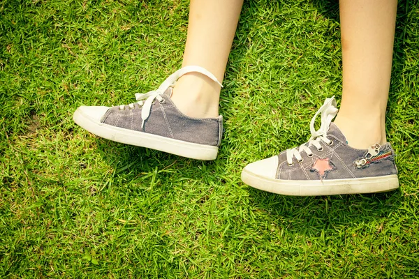 Youth sneakers on girl legs on grass during sunny serene summer — Stock Photo, Image