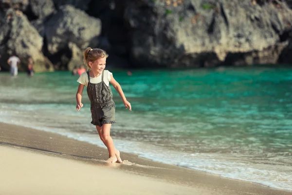 Glückliches kleines Mädchen, das tagsüber am Strand spazieren geht — Stockfoto