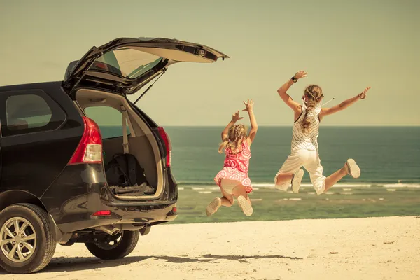 Two sisters standing near a car on the beach — Stock Photo, Image