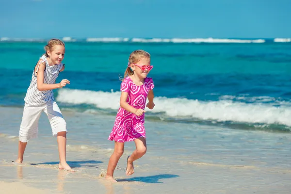 Dos hermanas corriendo en la playa durante el día — Foto de Stock