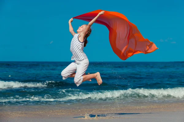Девочка-подросток, прыгающая по пляжу на голубом берегу моря на летних каникулах — стоковое фото