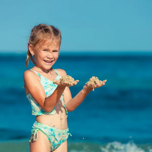 Liten flicka stående på stranden under dagarna — Stockfoto