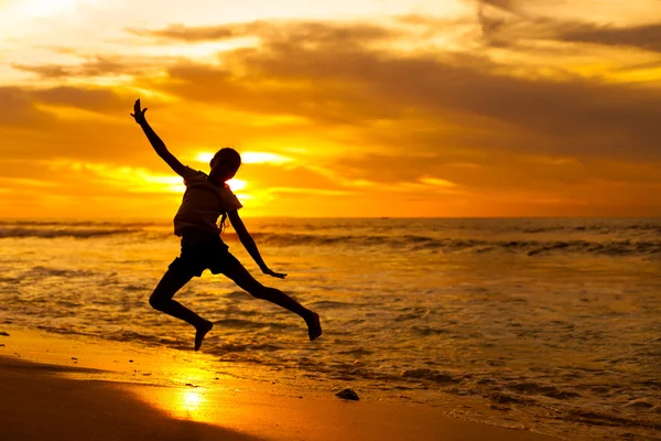 Happy girl jumping on the beach on the dawn time Stock Picture
