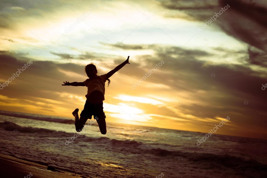 Happy girl jumping on the beach on the dawn time