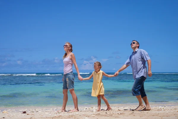 Glückliche Familie spazieren am Strand tagsüber — Stockfoto