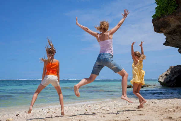 Familia feliz saltando en la playa durante el día — Foto de Stock