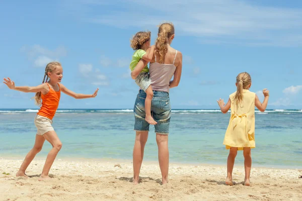 Glückliche Familie spielt tagsüber am Strand — Stockfoto