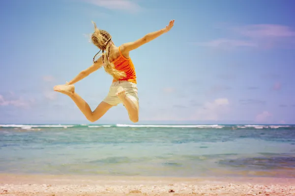 Прыгунья с трамплина девушка на голубом берегу моря во время летних каникул Лицензионные Стоковые Изображения