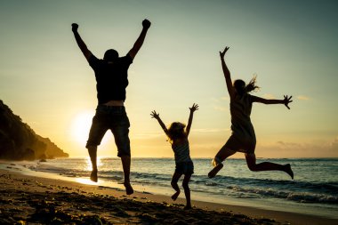 mutlu bir aile sahilde gündoğumu zaman atlama