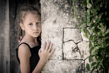taş duvara yakın günlerde ayakta üzgün küçük kız portresi 