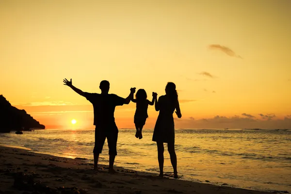 Lycklig familj spelar på stranden i tidens gryning — Stockfoto