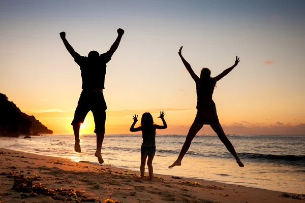 Glückliche Familie springt tagsüber am Strand — Stockfoto