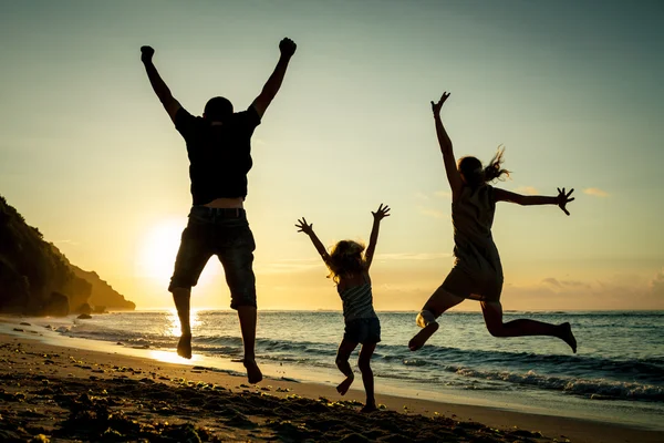 Happy family jumping on the beach at the sunrise time — Stock Photo, Image