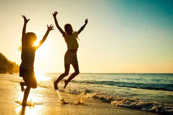 Anak-anak bahagia bermain di pantai pada waktu matahari terbit — Stok Foto