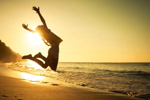 Teen flicka hoppning på stranden på dagarna — Stockfoto