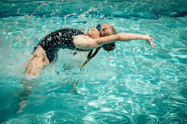 Menina adolescente pulando na piscina durante o dia — Fotografia de Stock