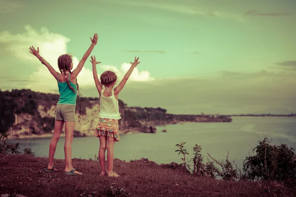 Two sisters standing on the beach and pulled up his hands — Stock Photo, Image