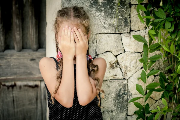 Portret smutny dziewczynka stojący w pobliżu kamiennego muru w dzień — Zdjęcie stockowe