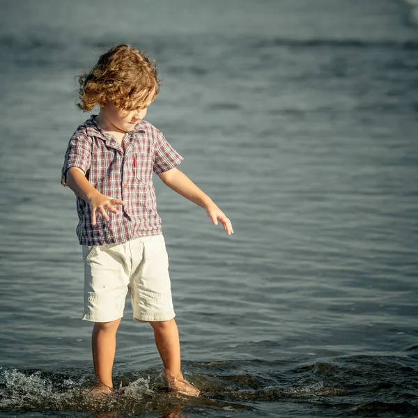 Маленький мальчик играет на пляже в дневное время — стоковое фото
