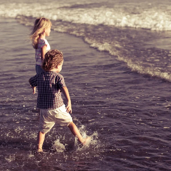 Niños felices jugando en la playa durante el día — Foto de Stock