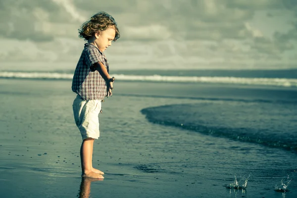 Маленький хлопчик грає на пляжі в той час — стокове фото