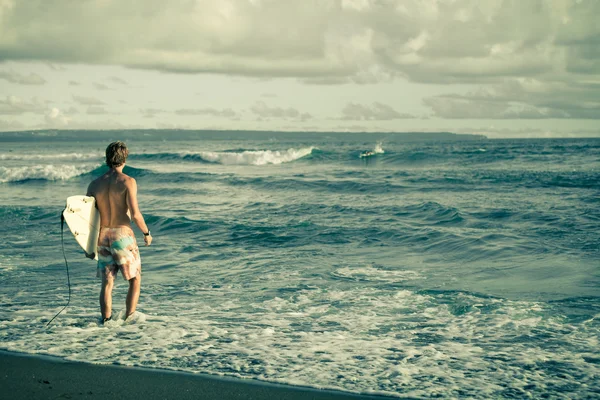 Серфер с доской для серфинга гуляет по пляжу днем — стоковое фото