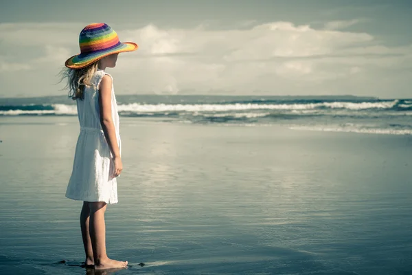 Triste menina de pé na praia durante o dia — Fotografia de Stock