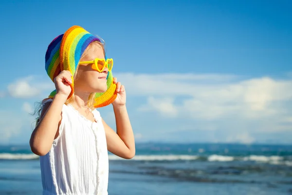 Glad liten tjej i hatt står på stranden i dag t — Stockfoto